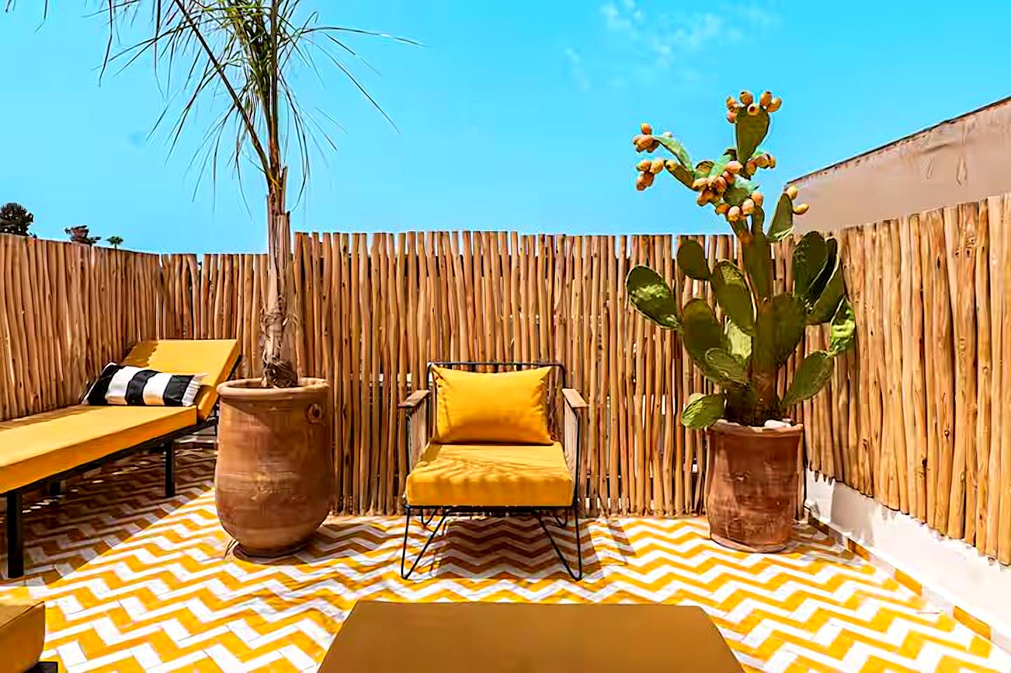 Terrasse privée de Riad Sasha, mobilier moutarde et carrelage chevron jaune sous le ciel bleu
