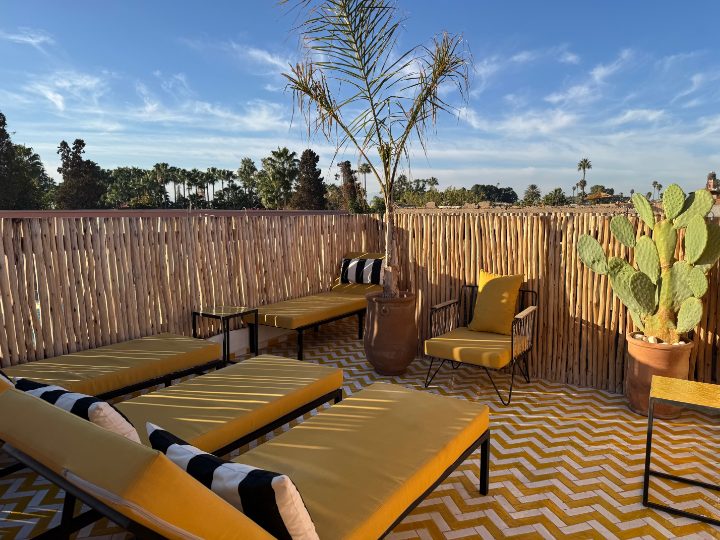 Terrasse de Riad Sasha au soleil couchant, transats jaunes et vue sur la palmeraie